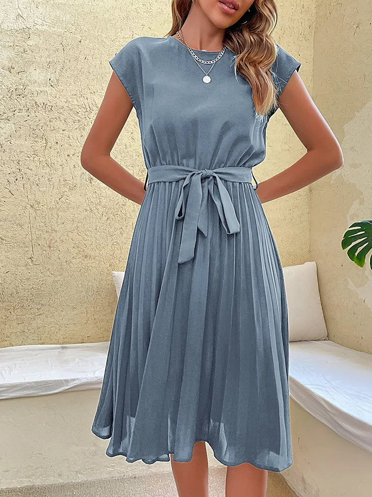 Elegant blue pleated summer beach dress for women with cap sleeves and a waist tie belt on neutral background