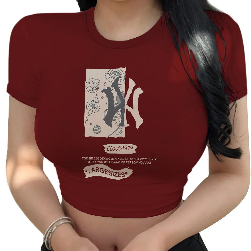 Woman wearing a fitted maroon crop top with abstract graphic design and text on front, paired with black bottoms