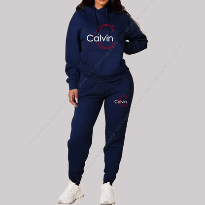 Woman wearing navy blue two-piece designer tracksuit with hoodie and jogger pants, white sneakers.