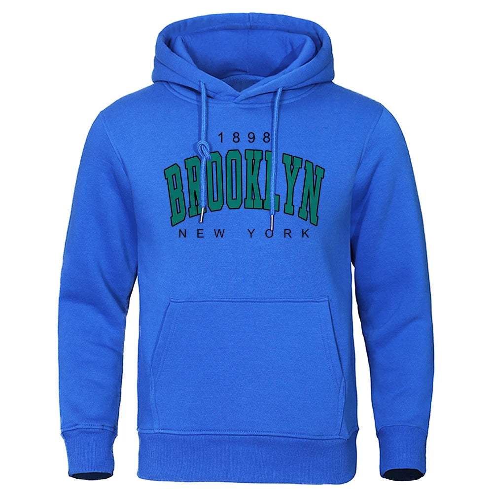 Blue men's hoodie with Brooklyn New York vintage text, front pocket, and drawstring hood on white background