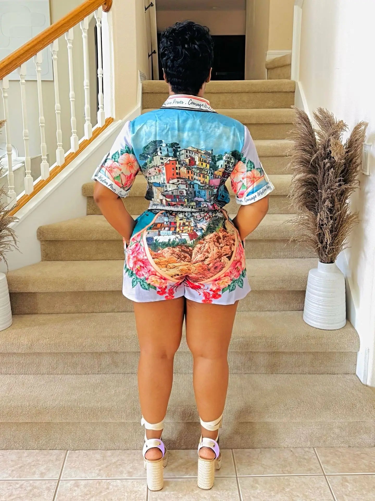 Woman wearing a colorful two-piece summer outfit with a scenic print short-sleeve shirt and matching shorts