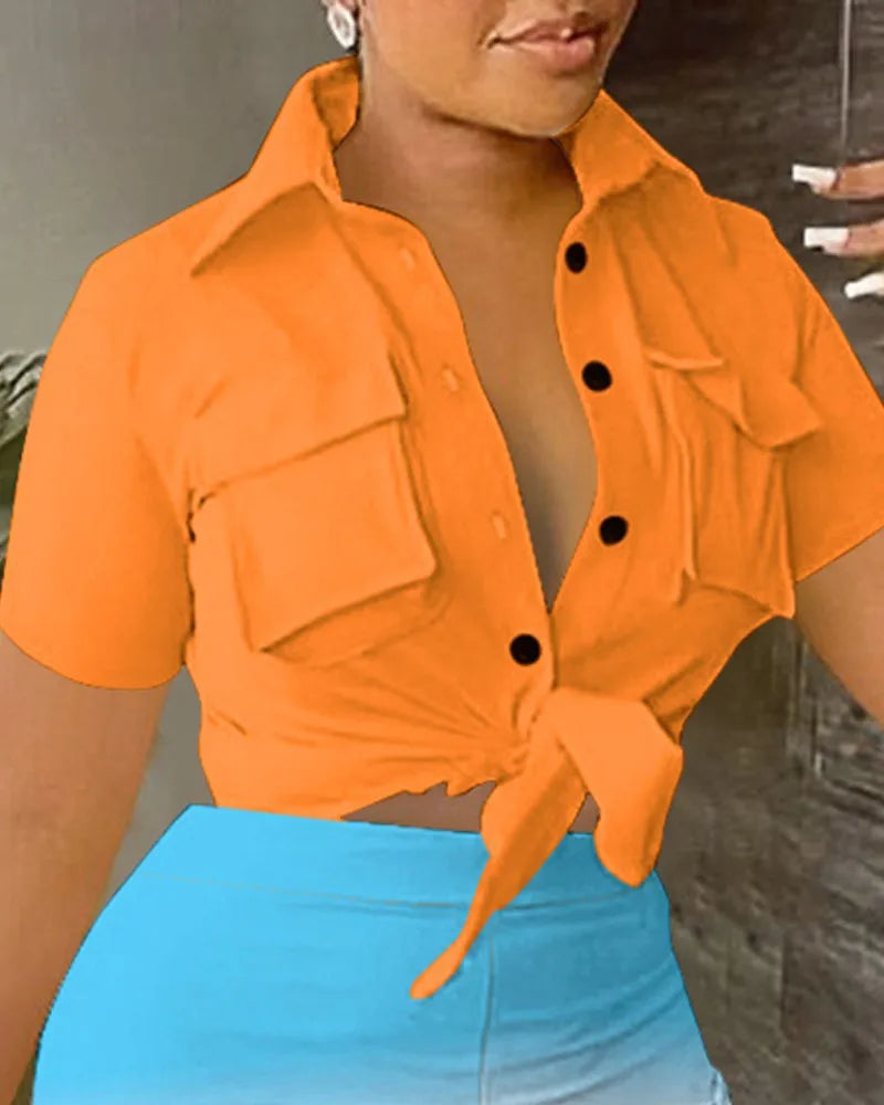 Woman wearing an orange short-sleeve tie-front crop top with large pockets and high-waisted blue shorts summer outfit