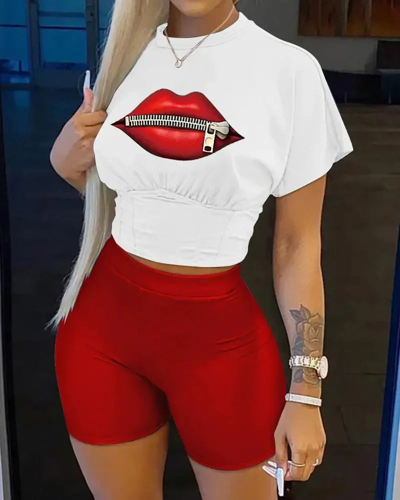 Woman wearing a white crop top with red lips zipper graphic and fitted high-waisted red biker shorts two-piece set