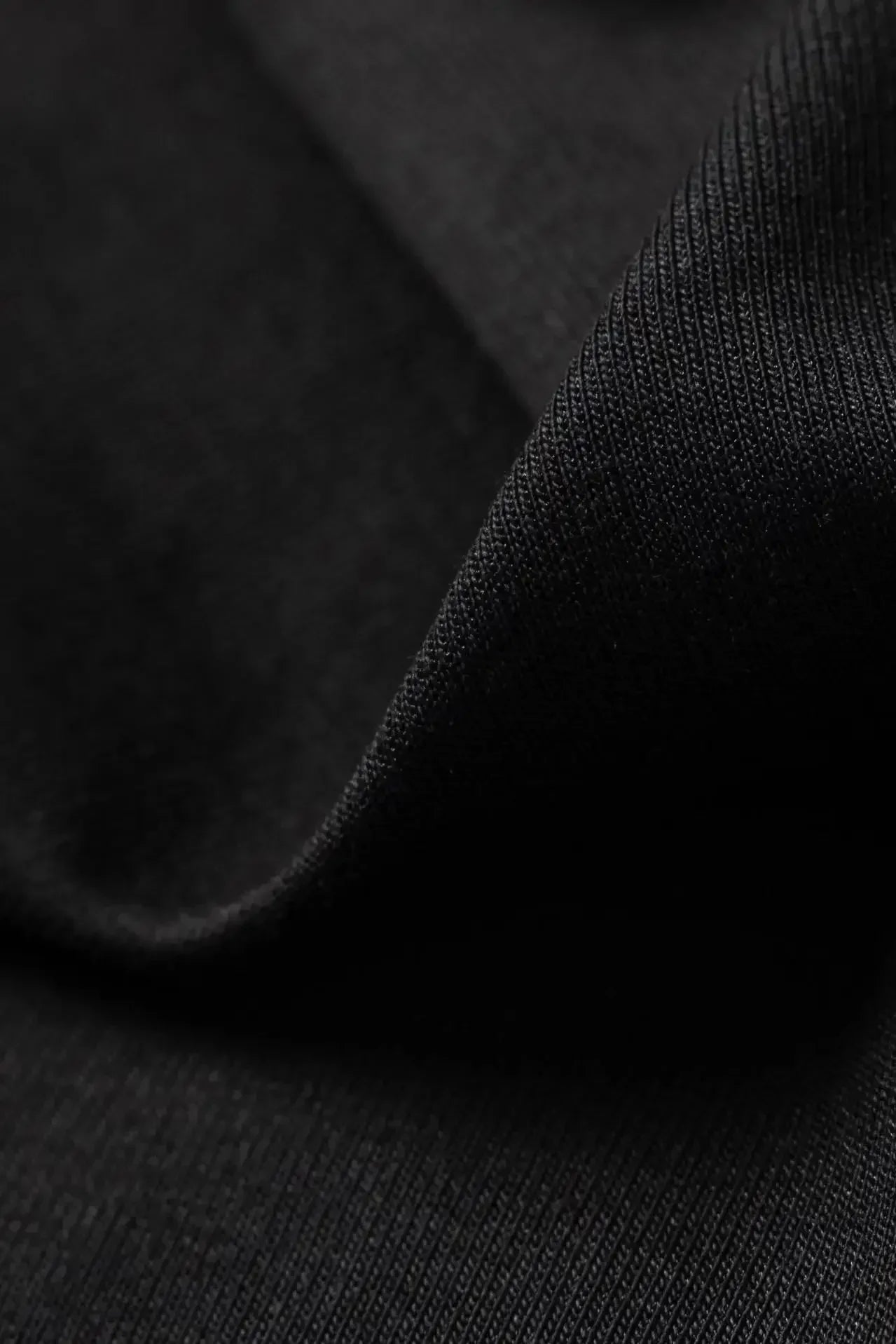 Close-up of black fabric texture showing fine knit detail and soft material of the t-shirt garment
