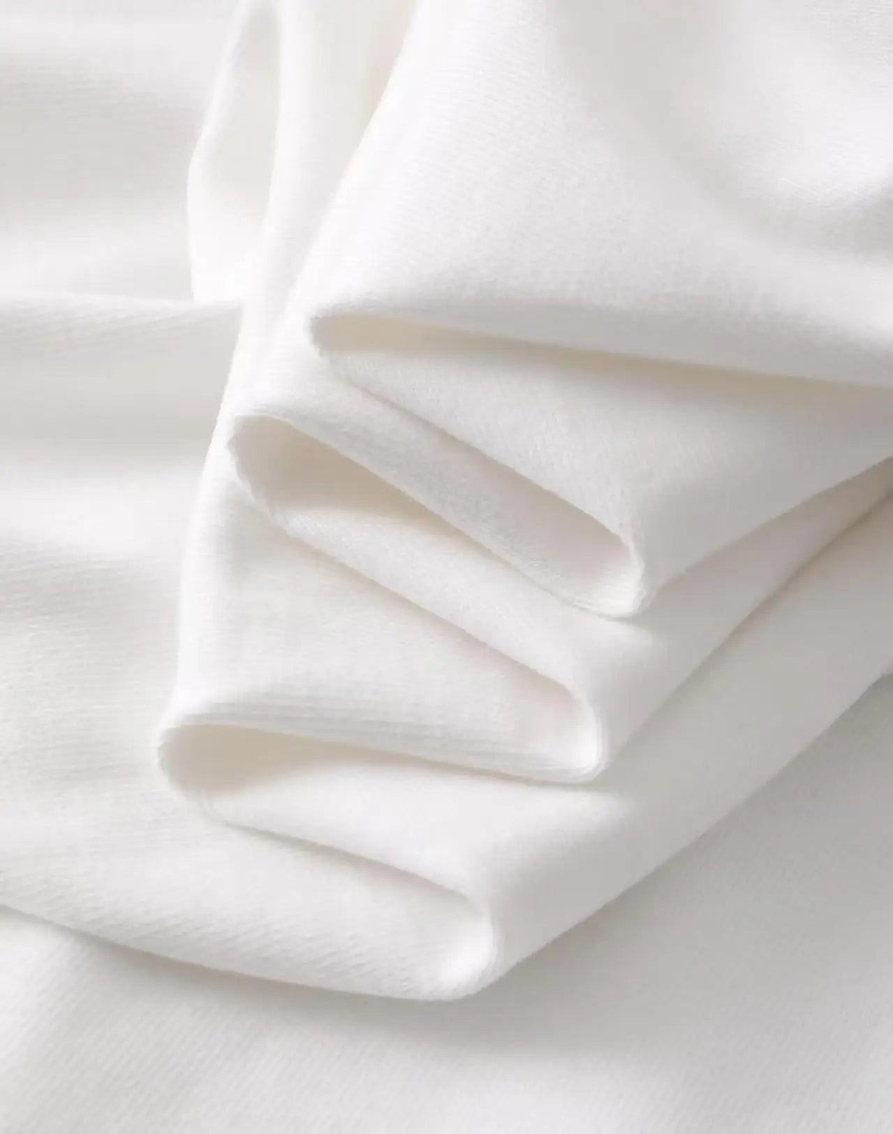 Close-up of soft folded white fabric detail for a Harajuku style artistic painted face t-shirt