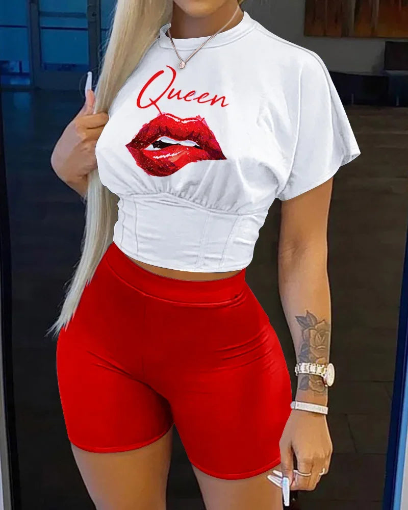 Woman wearing white cropped t-shirt with red lips and queen text paired with bright red fitted shorts
