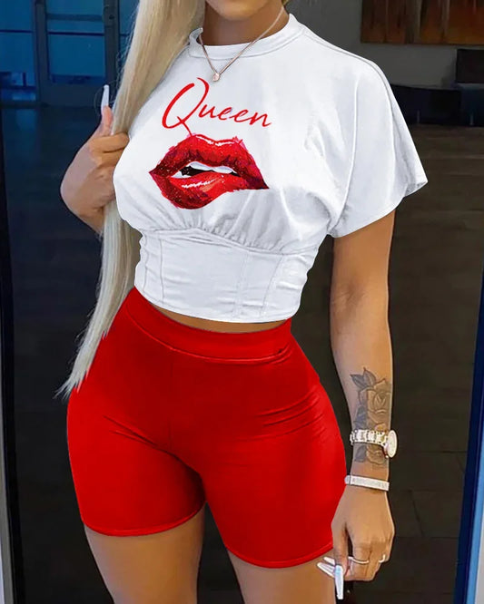 Woman wearing white cropped t-shirt with red lips and queen text paired with bright red fitted shorts