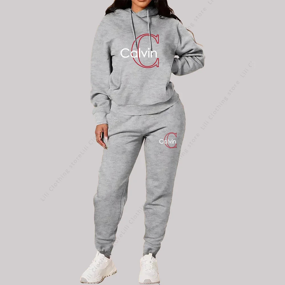 Woman wearing grey designer 2-piece tracksuit with hoodie and pants, featuring Calvin logo in red and white text