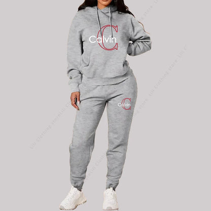 Woman wearing grey designer 2-piece tracksuit with hoodie and pants, featuring Calvin logo in red and white text