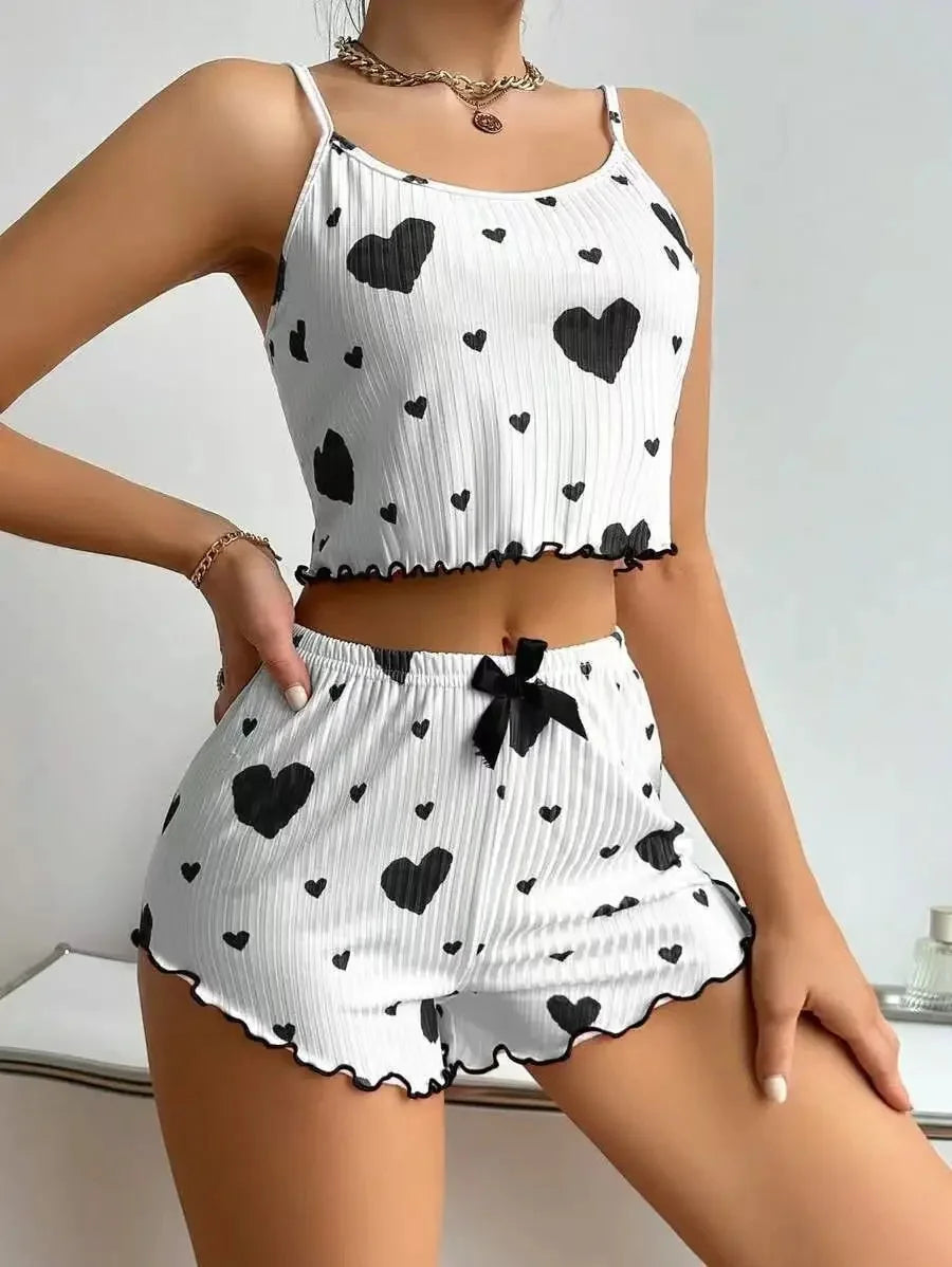 Woman wearing a white ribbed two-piece pajama set with black heart prints and black trim details