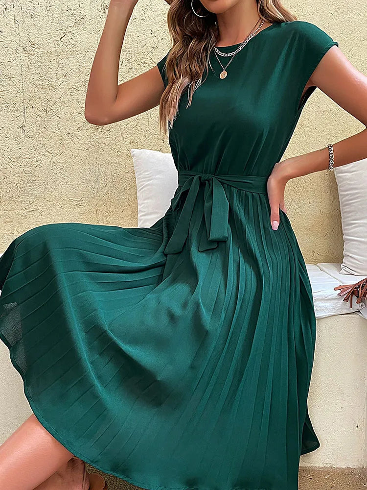 Elegant green pleated summer beach dress for women with short sleeves and waist tie belt on neutral background