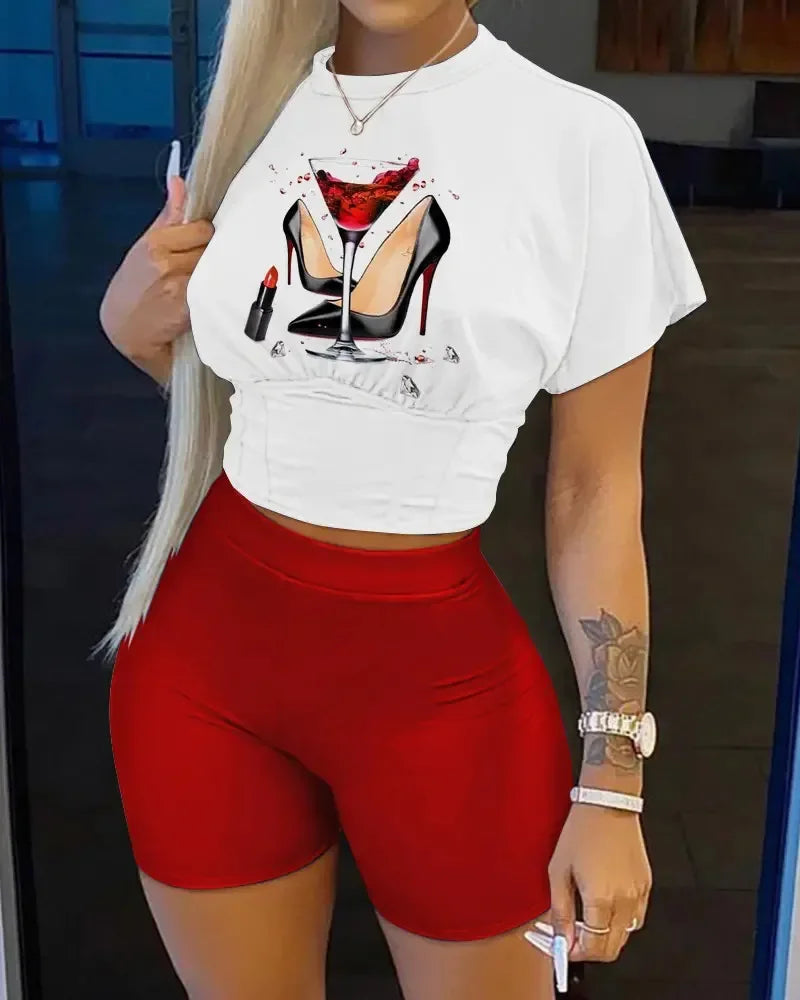 Woman wearing a white cropped graphic t-shirt with heels and lipstick print and fitted red biker shorts summer outfit