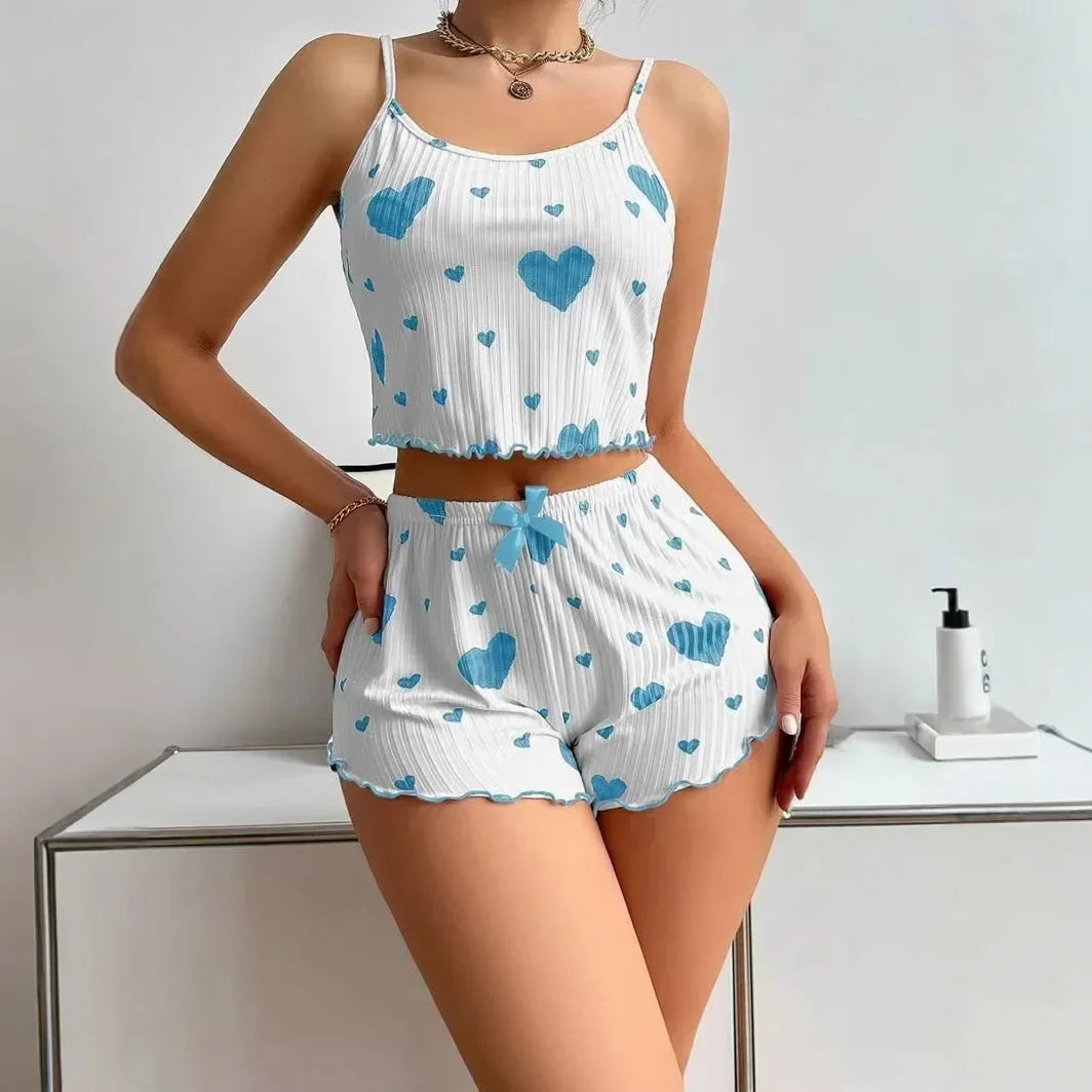 Woman wearing a white two-piece pajama set with blue heart print, cropped tank top and matching shorts