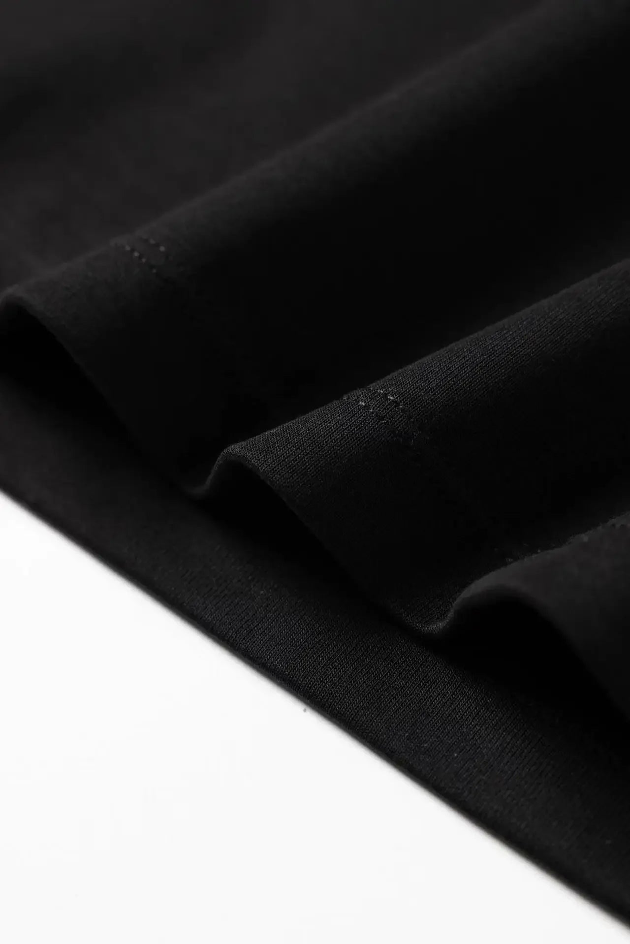 Close-up of black fabric hem detail on a Harajuku streetwear artistic t-shirt for women