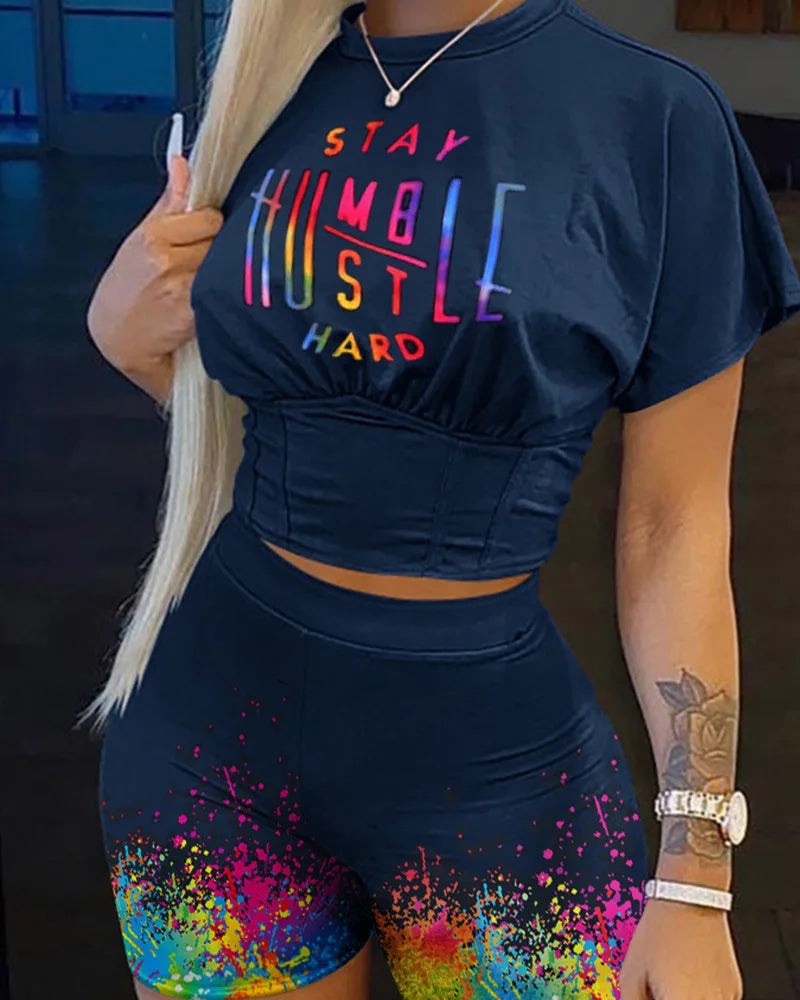 Woman wearing black cropped t-shirt with colorful text and matching shorts with vibrant paint splash design