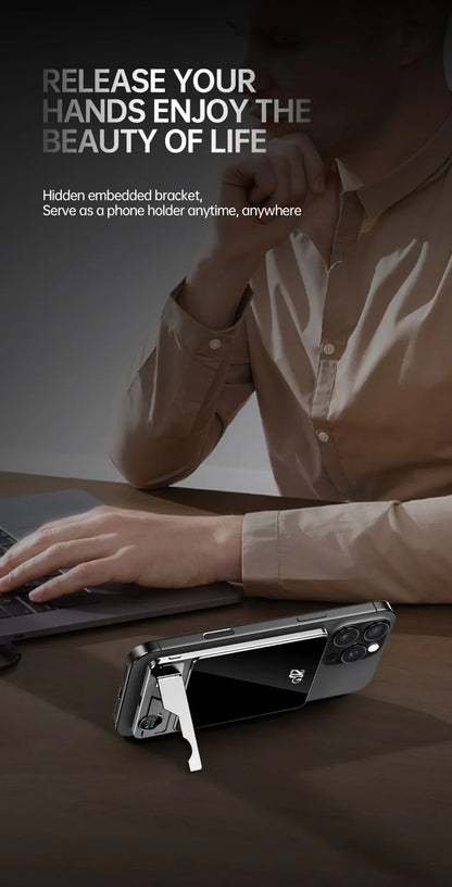 Black power bank with hidden bracket propping up smartphone on table next to person working on laptop