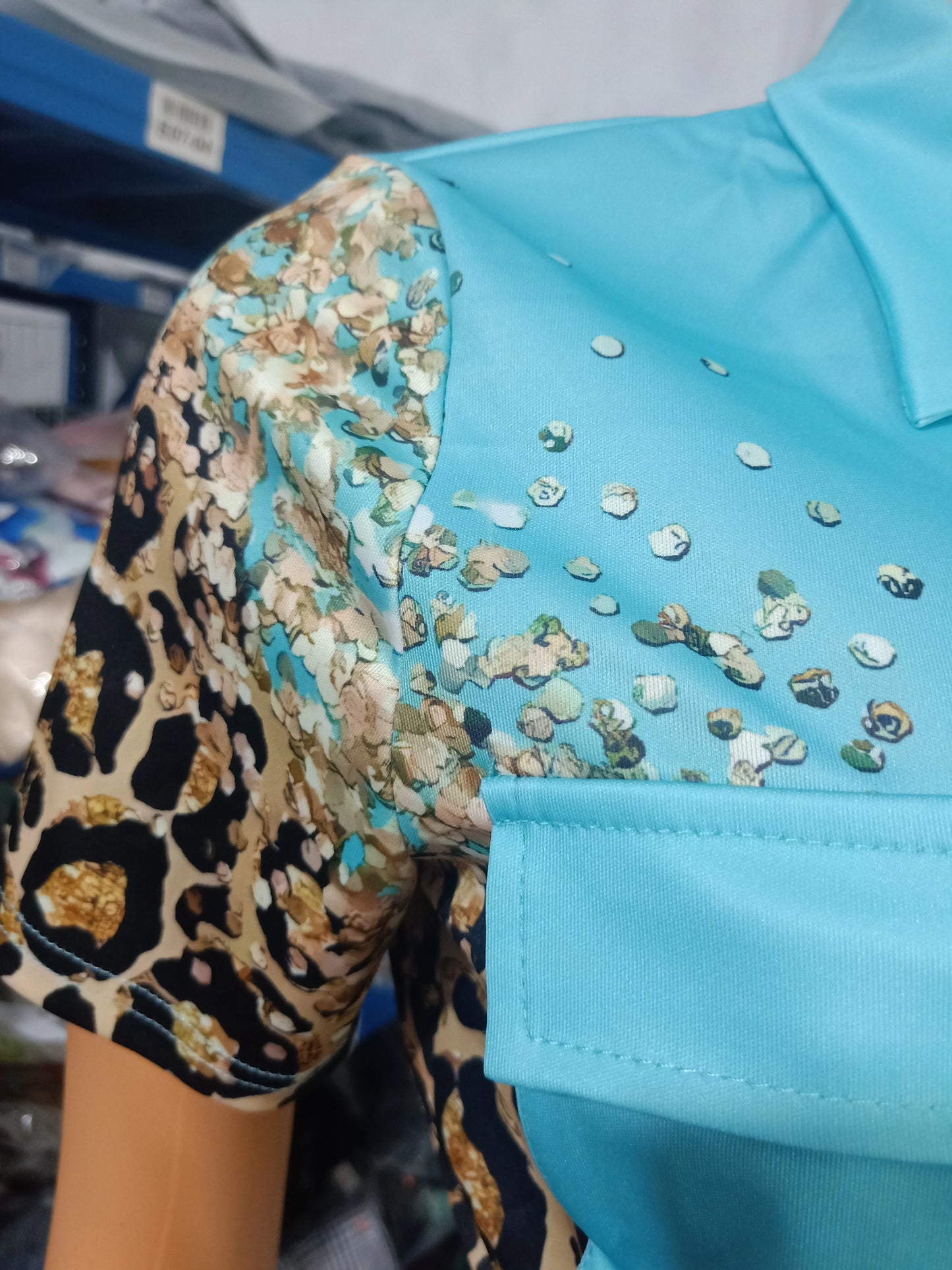 Close-up of a summer two-piece outfit with a blue top and short sleeve featuring leopard and floral print details