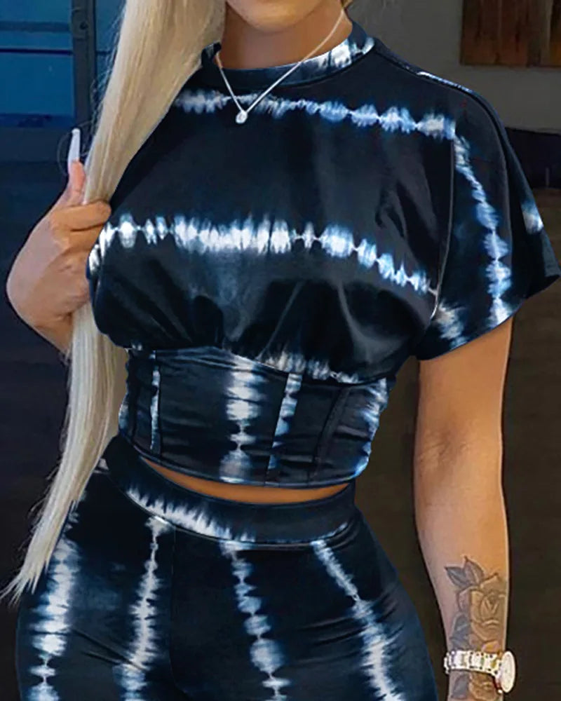 Woman wearing a black and white tie-dye two-piece outfit consisting of a cropped t-shirt and matching high-waisted shorts