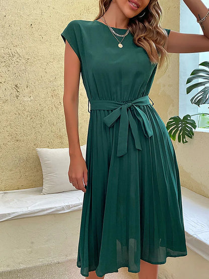 Elegant green pleated summer beach dress for women with belt, short sleeves, and casual fit on neutral background