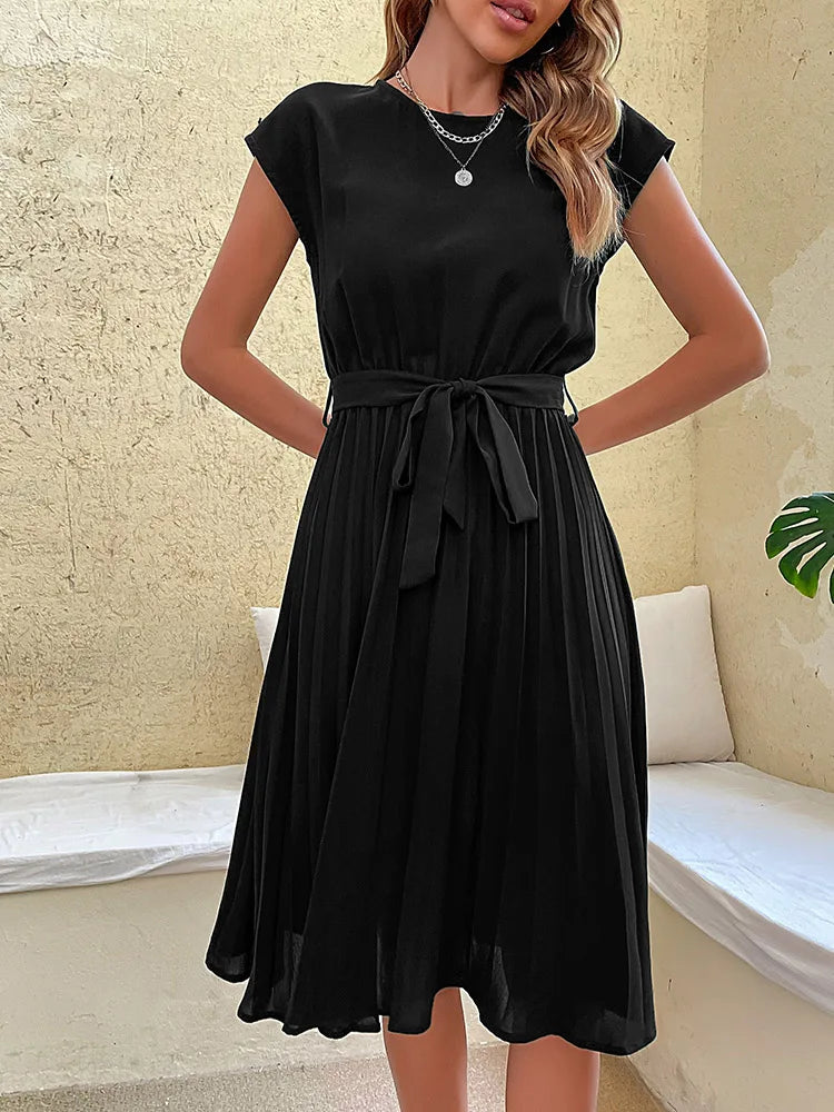 Black summer beach dress for women with pleated skirt and waist tie, elegant and casual style on neutral background