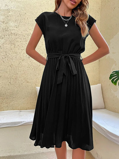 Black summer beach dress for women with pleated skirt and waist tie, elegant and casual style on neutral background