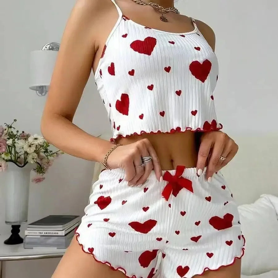 Woman wearing a white two-piece pajama set with red heart print and red bow on elastic waist shorts