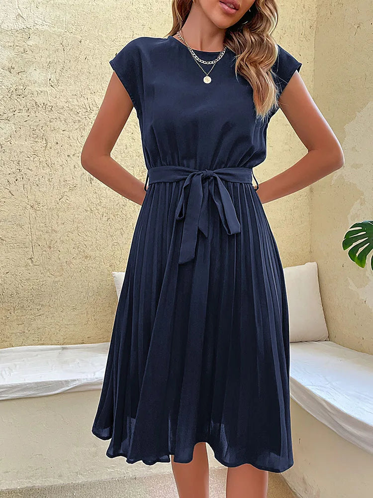 Elegant navy blue pleated summer beach dress for women with cap sleeves and waist tie belt on neutral background