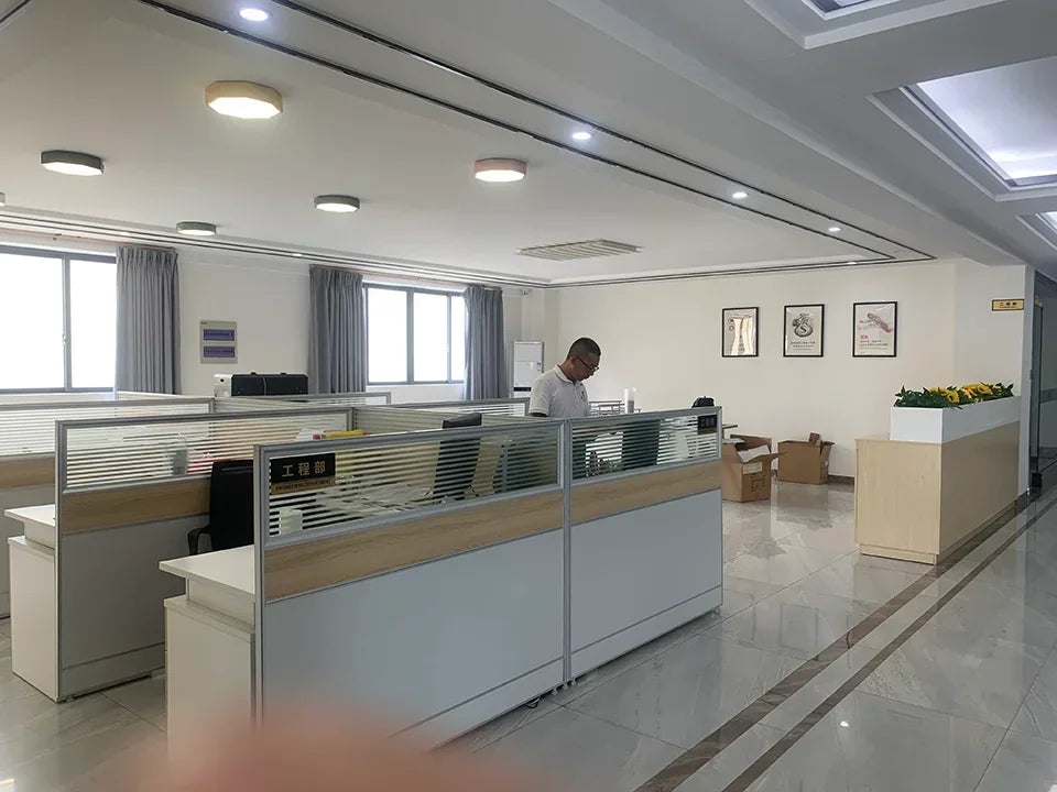 Man working alone in a modern office cubicle area with large windows and minimal decor