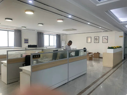 Man working alone in a modern office cubicle area with large windows and minimal decor
