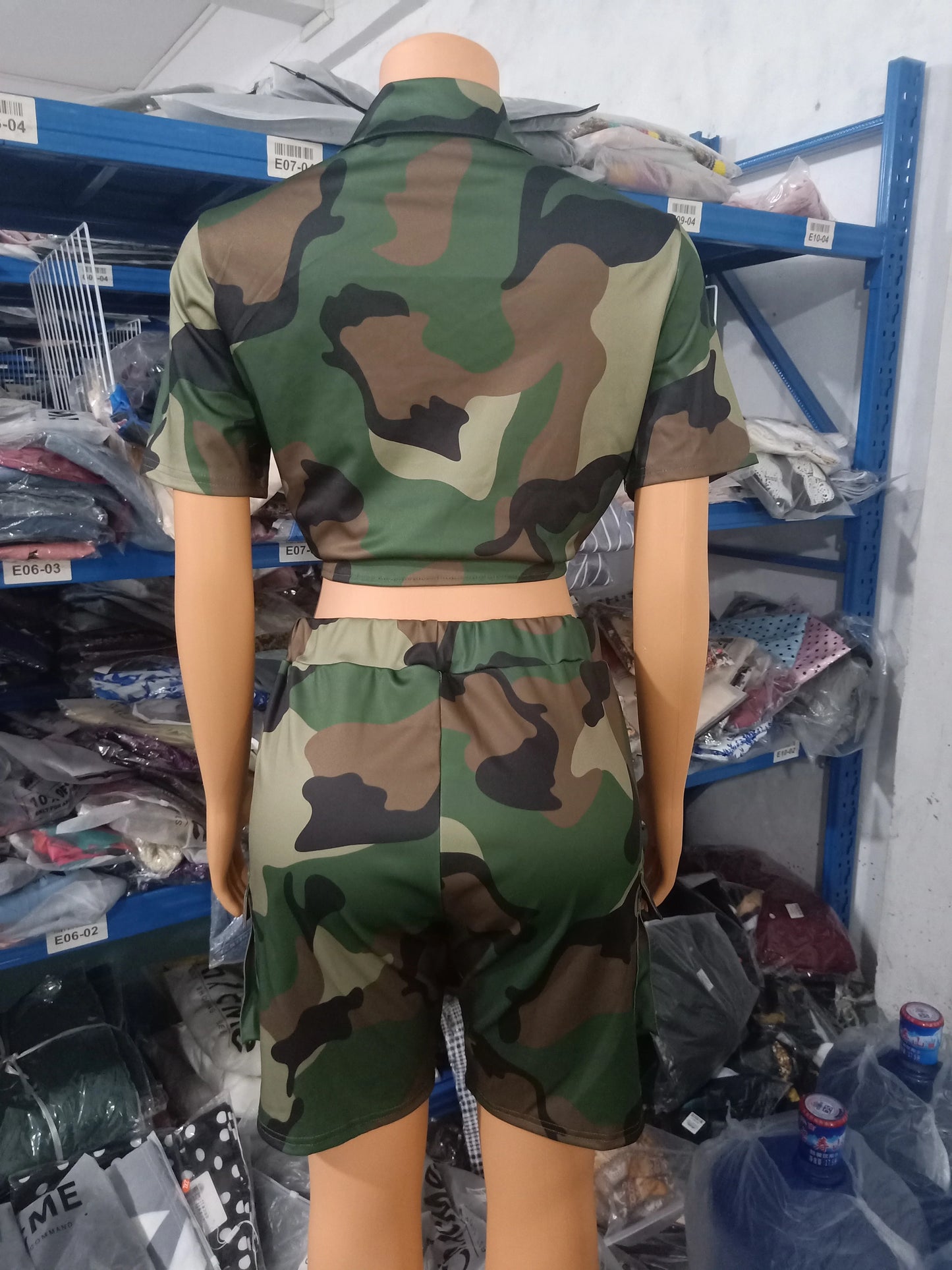 Female mannequin wearing a camouflage two-piece summer outfit with a short-sleeve cropped top and matching shorts