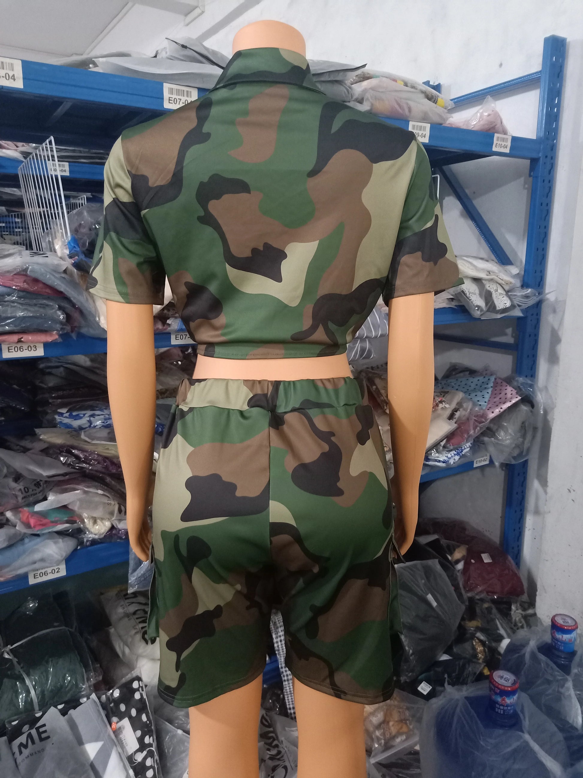 Female mannequin wearing a camouflage two-piece summer outfit with a short-sleeve cropped top and matching shorts