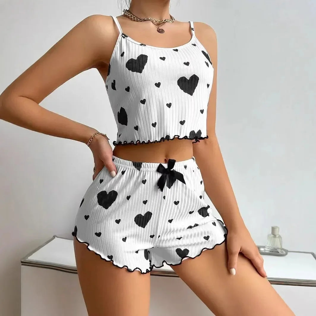 Woman wearing a white ribbed two-piece pajama set with black heart prints and ruffled edges for comfortable sleepwear