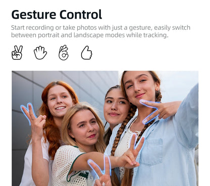 Four young women smiling and posing with hand gestures for a selfie outdoors against a gray wall
