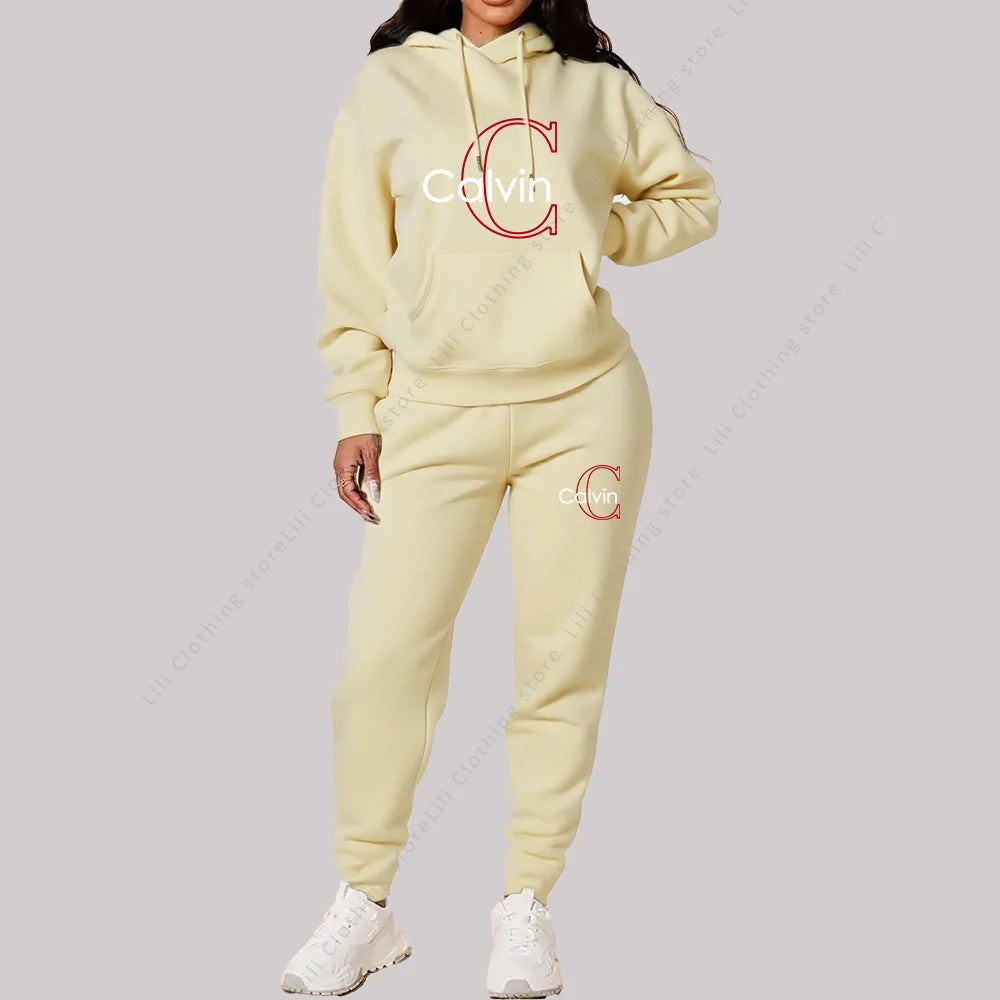 Woman wearing a beige designer two-piece tracksuit with hoodie and jogger pants on a plain background