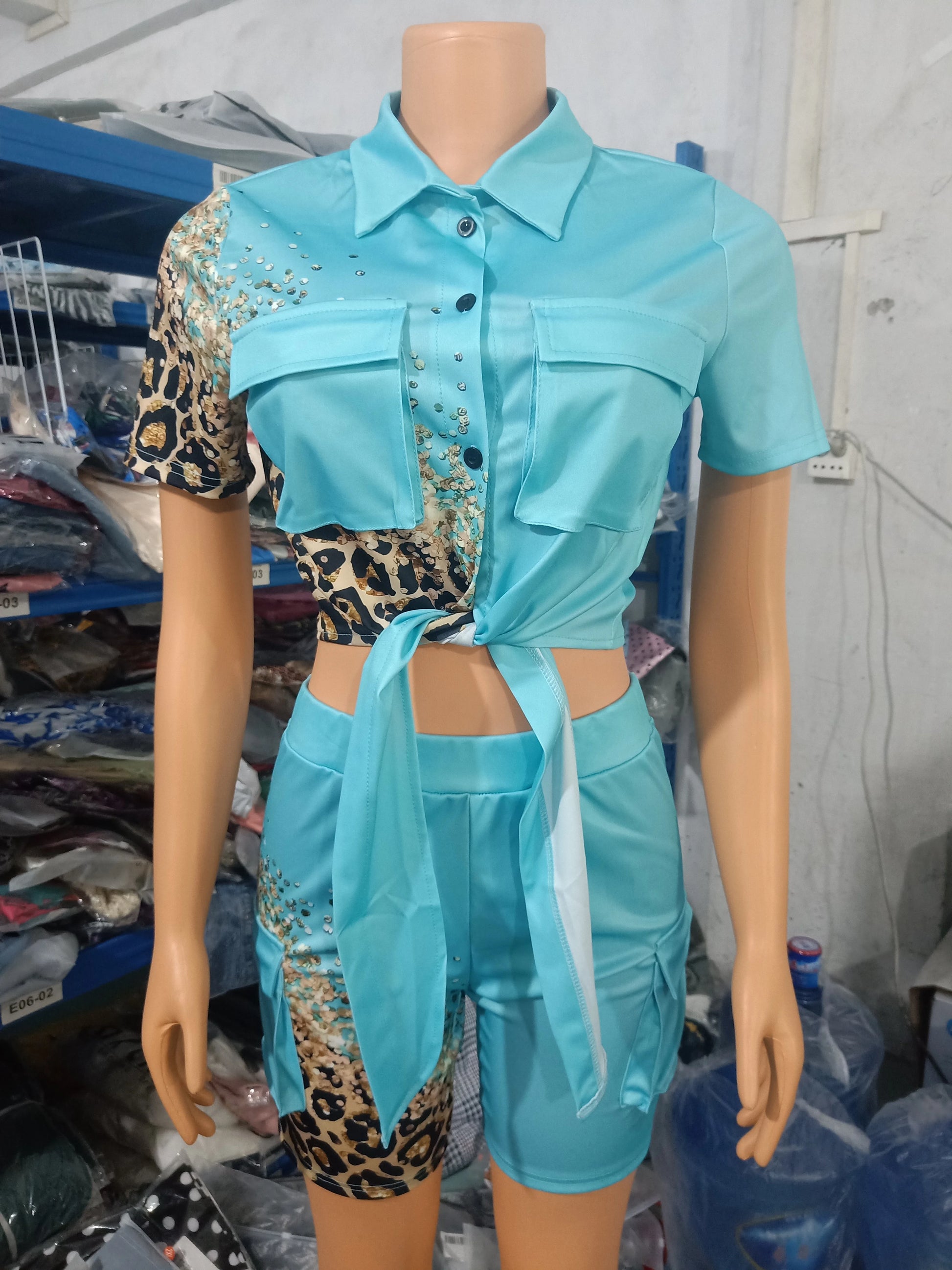 Female mannequin wearing a turquoise two-piece summer outfit with leopard print accents and a tied crop top with shorts