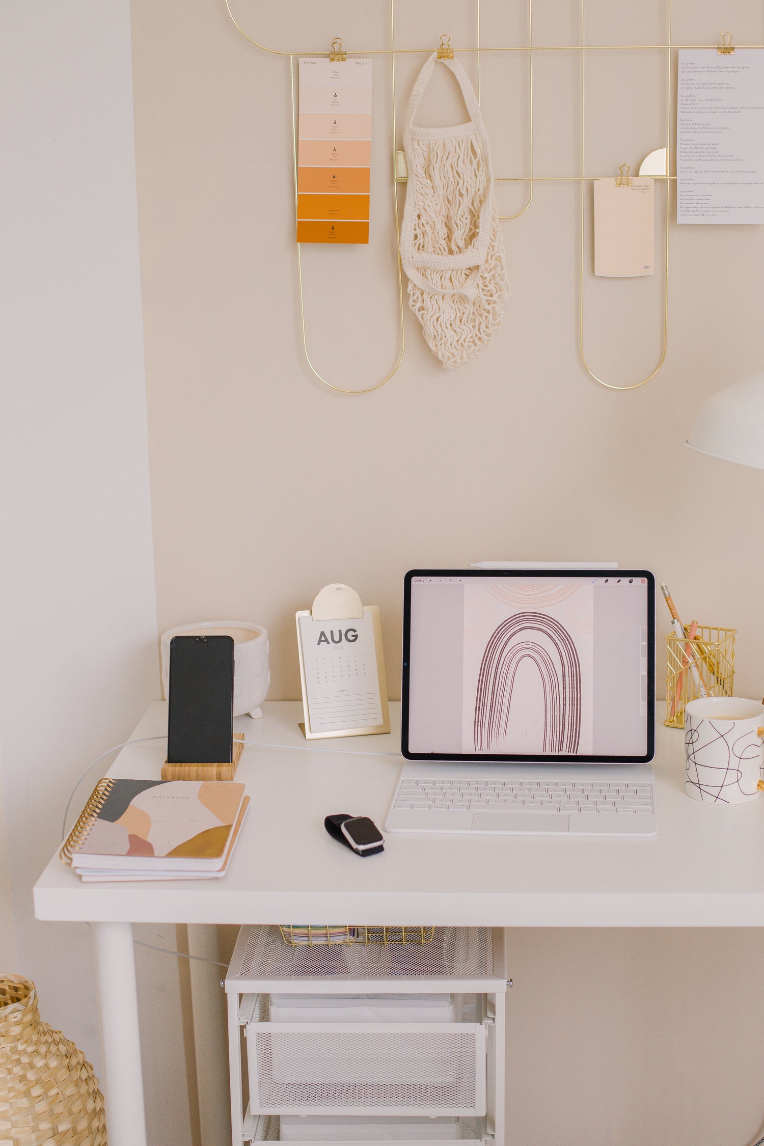 Minimalist workspace with tablet, smartphone, notebook, and calendar on white desk against beige wall